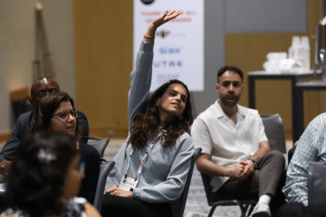 Conference attendee raising hand during session